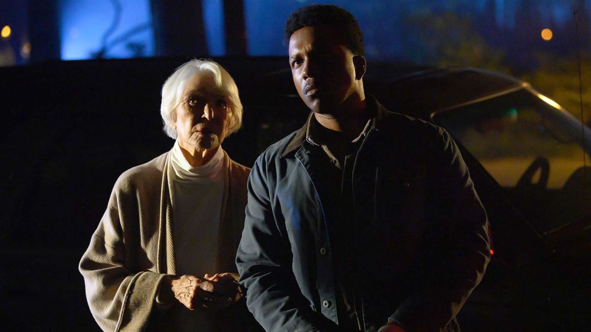 Ellen Burstyn and Leslie Odom Jr. stand next to each other at night in The Exorcist: Believer