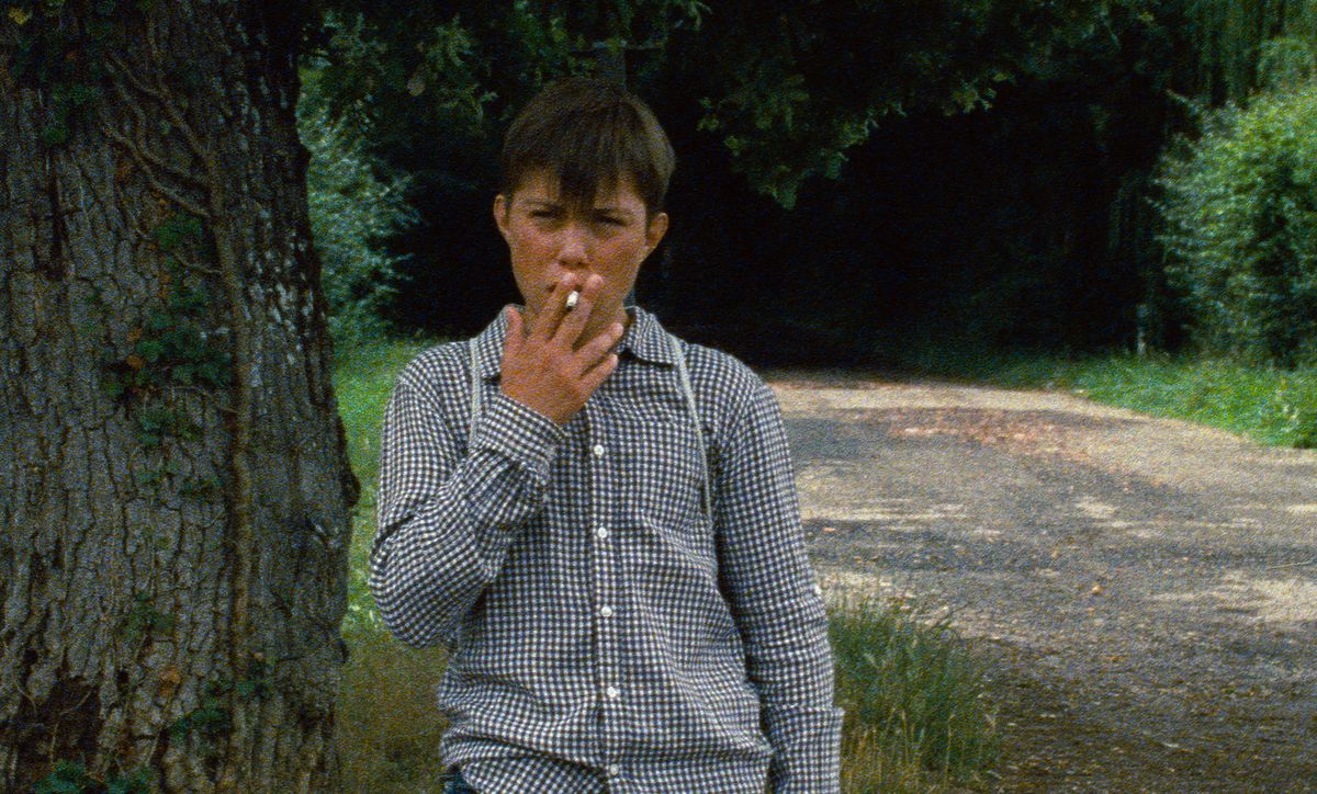 En mycket ung pojke röker en cigarett i en kornig bild från Astrakan