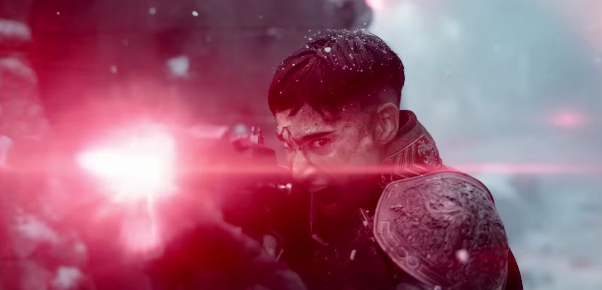 En mörkhårig karaktär i invecklad rustning avfyrar ett strålvapen som producerar ett starkt rosa ljus i Zack Snyders Rebel Moon