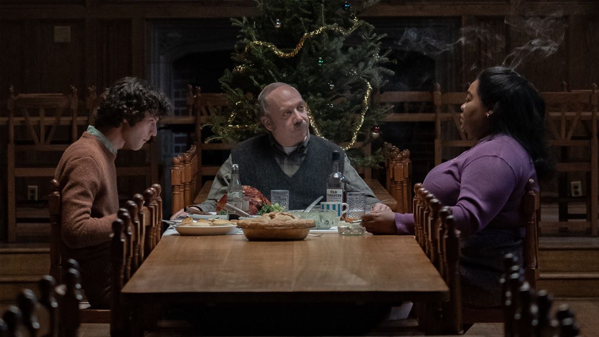 Dominic Sessa, Paul Giamatti och Da'Vine Joy Randolph samlas runt ett bord med en julgran i bakgrunden i The Holdovers.