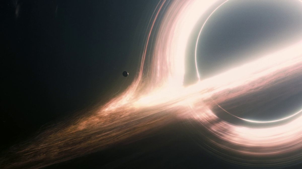 en bred bild av en liten planetoid som svävar vid händelsehorisonten för ett massivt svart hål i Interstellar.