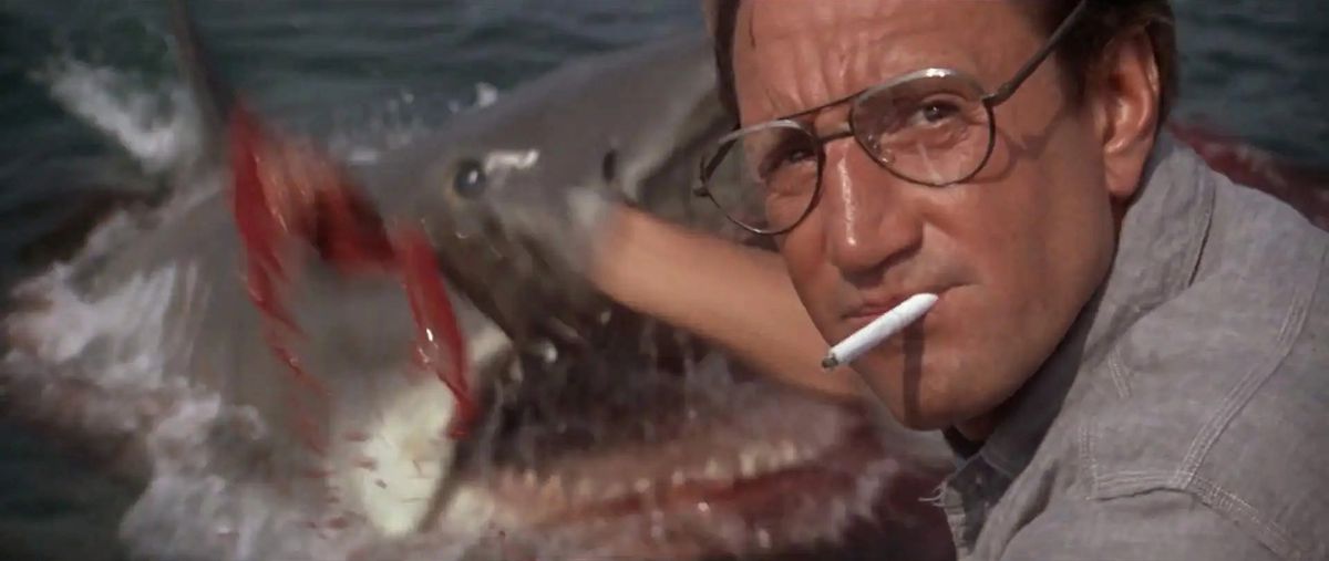 Roy Scheider som Martin Brody som öser ner kompisen i havet, omedveten om den stora vithajen som dyker upp i vattnet i Jaws.