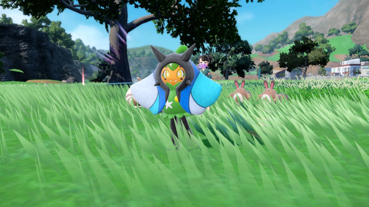 En blå Wellspring Ogerpon i Pokémon Scarlet och Violet i ett gräsbevuxet fält