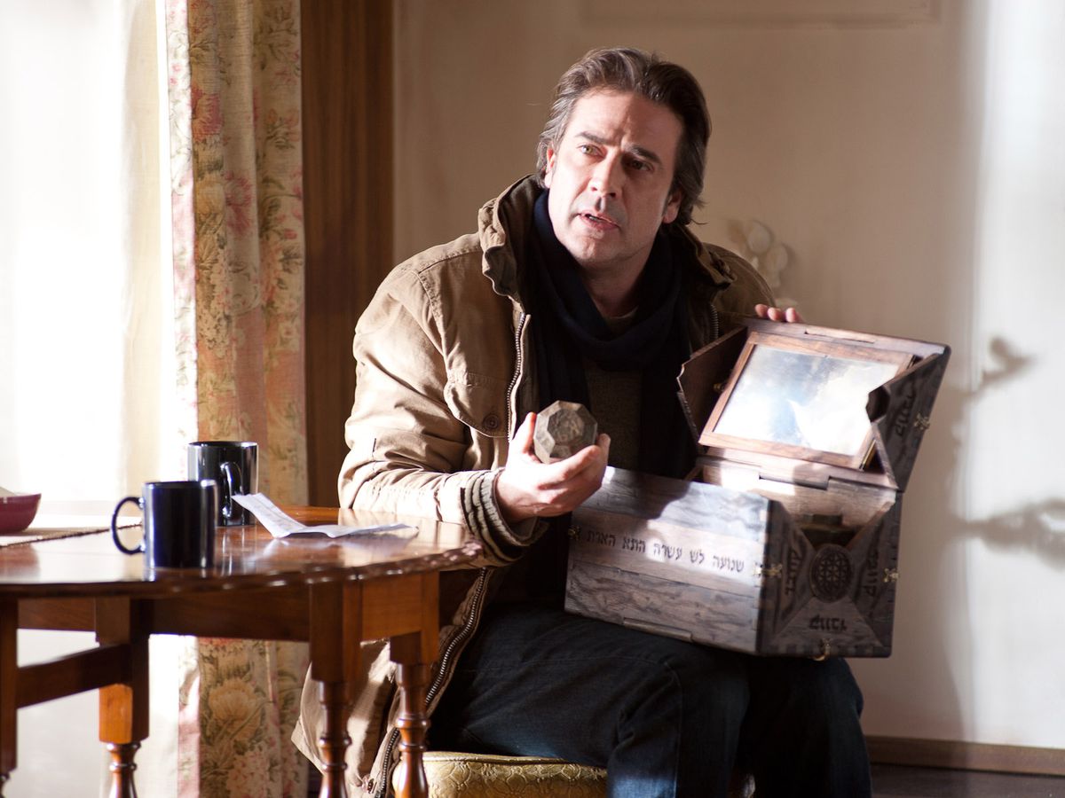 Jeffrey Dean Morgan som Clyde i The Possession sitter med en låda i knät och tar ut föremål ur den