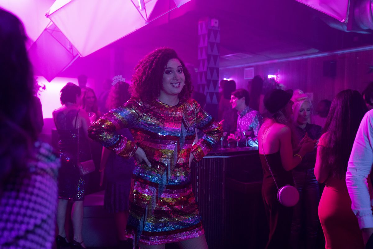 Rose Matafeo stands in a club, wearing a sparkling dress with her hands on her hips, in Starstruck.