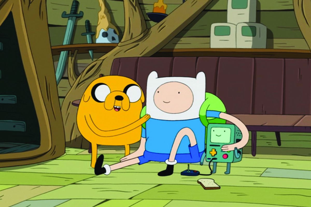 Jake the Dog, Finn the Human, and BMO hug it out on the floor of their treehouse in Adventure Time.