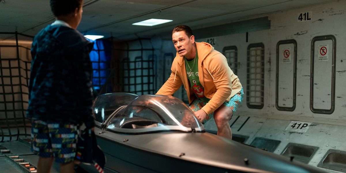 Den före detta Fast and Furious-skurken Jakob (John Cena) böjer sig över ett segelflygplan gömt i lastbrunnen på ett kommersiellt flygplan medan Little Brian (Leo Abelo Perry, med ryggen mot kameran) tittar på i Fast X