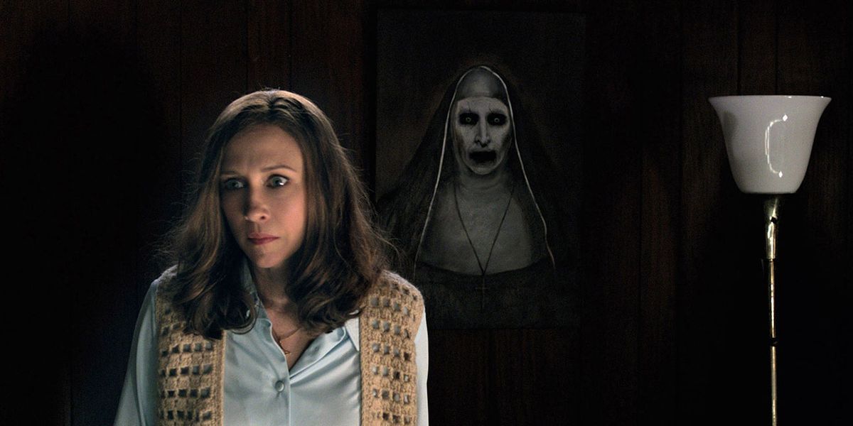 Vera Farmiga som Lorraine Warren står framför ett läskigt nunnaporträtt i The Conjuring 2