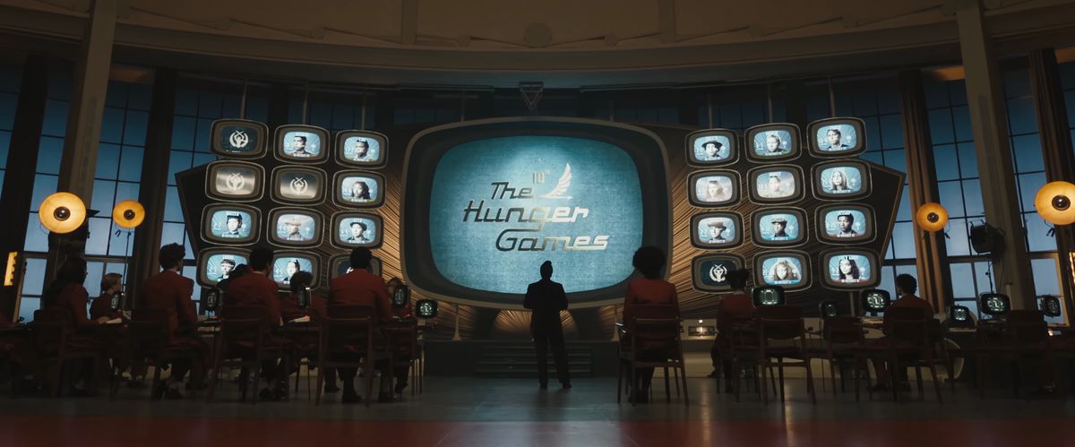 Världens logotyp för Hunger Games på retro-TV-skärmar medan anställda i spelen funderar