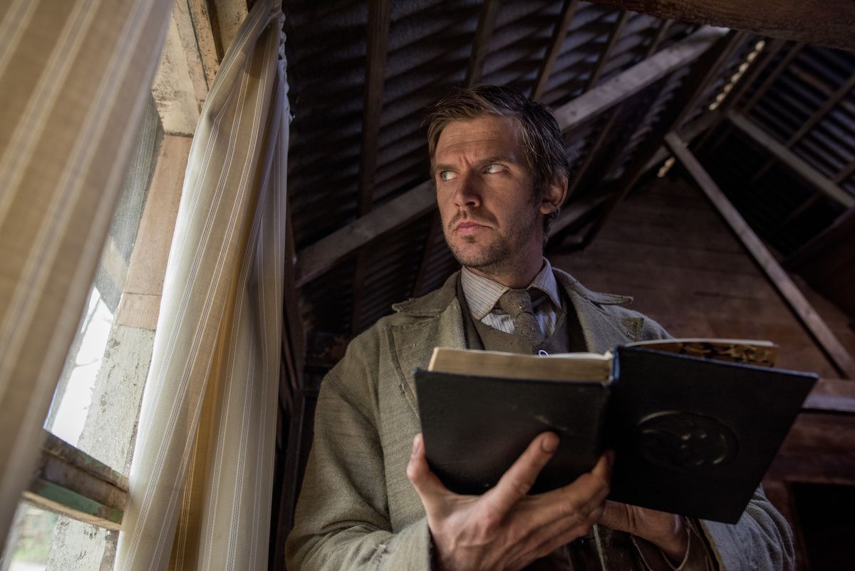 Dan Stevens som Thomas Richardson i Apostle tittar misstänksamt ut genom fönstret medan han läser Bibeln