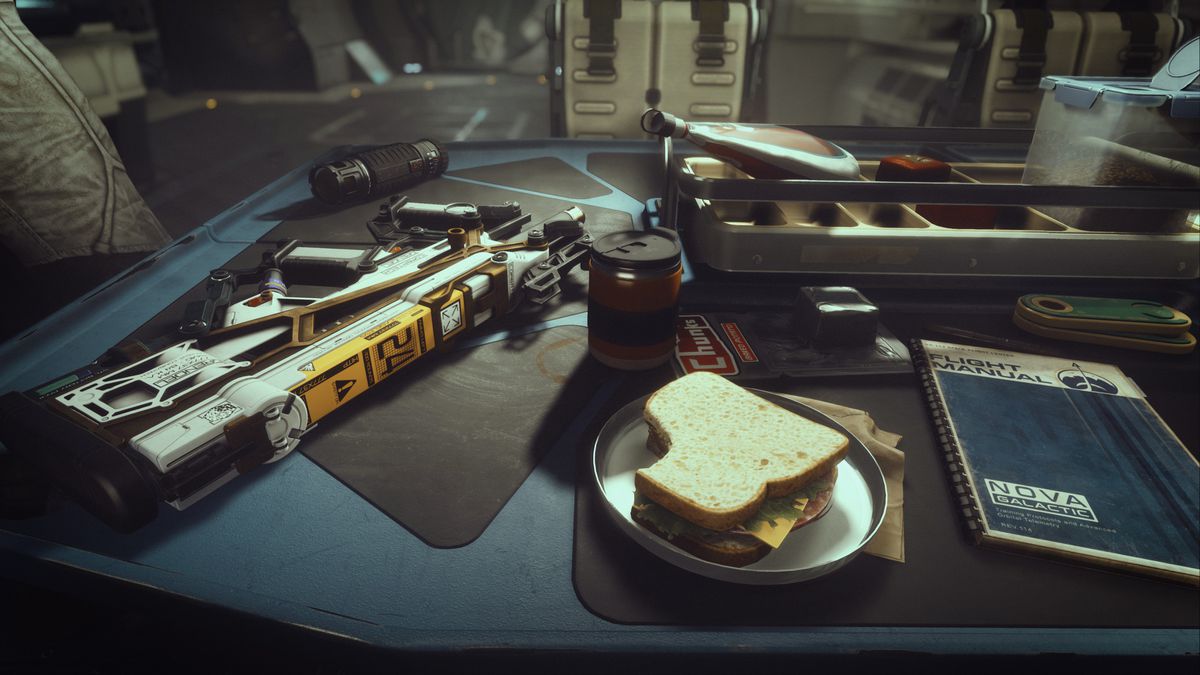 ett automatgevär, en flygmanual, en smörgås och andra föremål som sitter på ett skrivbord i Starfield