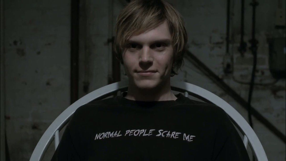 en blond tonårspojke i en svart t-shirt, han ser ond ut i American Horror Story
