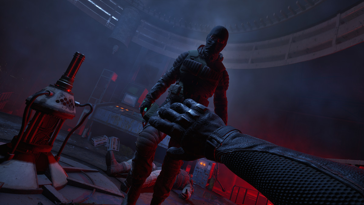 Spelarkaraktären lyfter en handskförsedd hand framför sin förstapersonsvy, som för att skydda sig från en maskerad figur som kommer emot dem i ett rödupplyst rum från STALKER 2