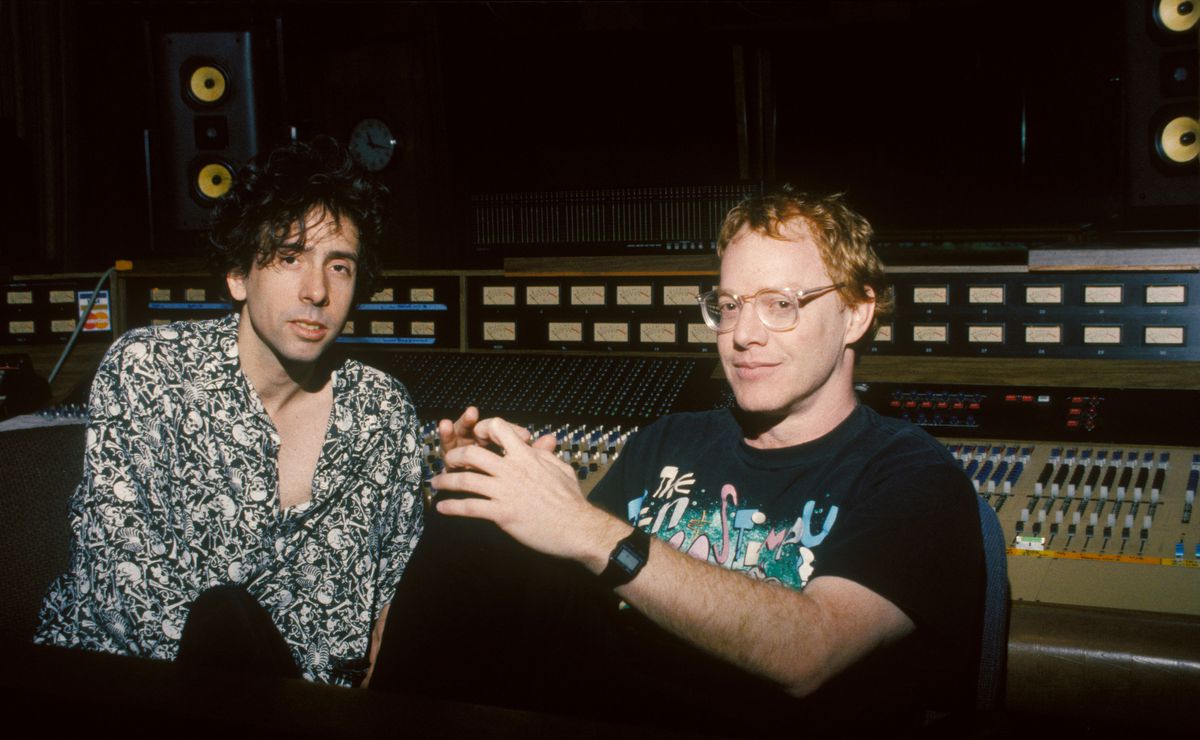 Tim Burton i en svart och vit button-down skjorta och Danny Elfman i en band-t-shirt, stora glasögon och en skum digital klocka, som sitter i inspelningsstudion för The Nightmare Before Christmas