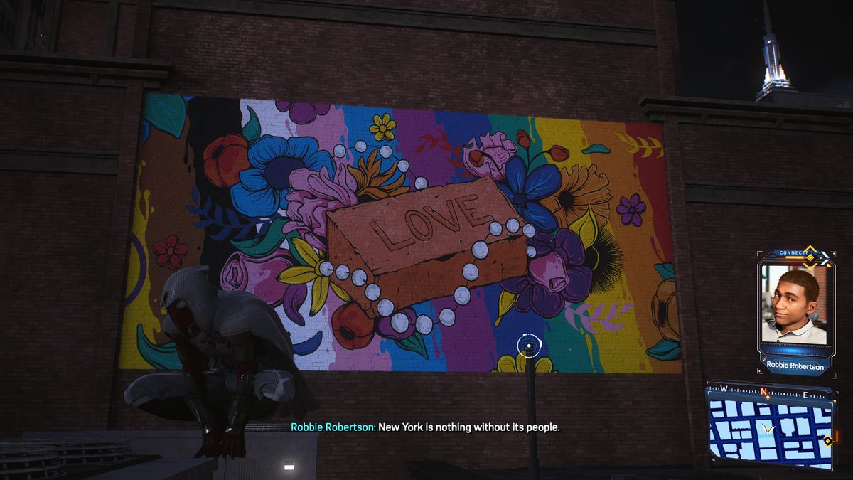 Miles Morales, iklädd en huvadräkt, hukar sig framför en väggmålning i New York i Marvels Spider-Man 2