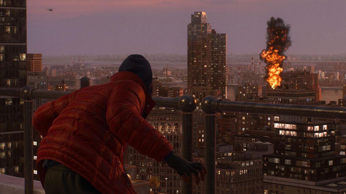 Miles Morales som Spider-Man, stående på ett hustak i Spider-Man 2, ser en explosion över staden