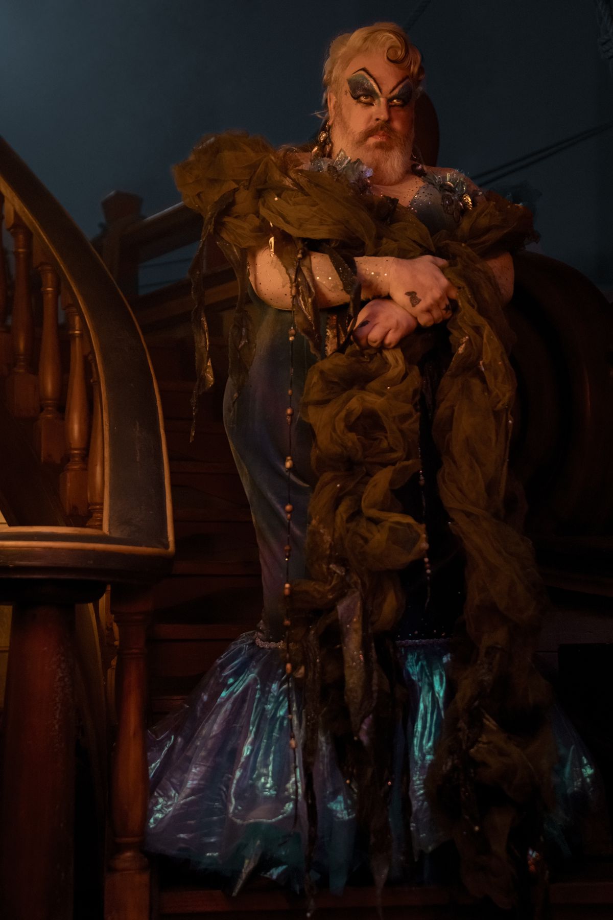 En bild av Wee John (Kristian Nairn) utklädd till Calypso, som ser formidabel ut i en klänning i sjöjungfrustil, med en gigantisk 