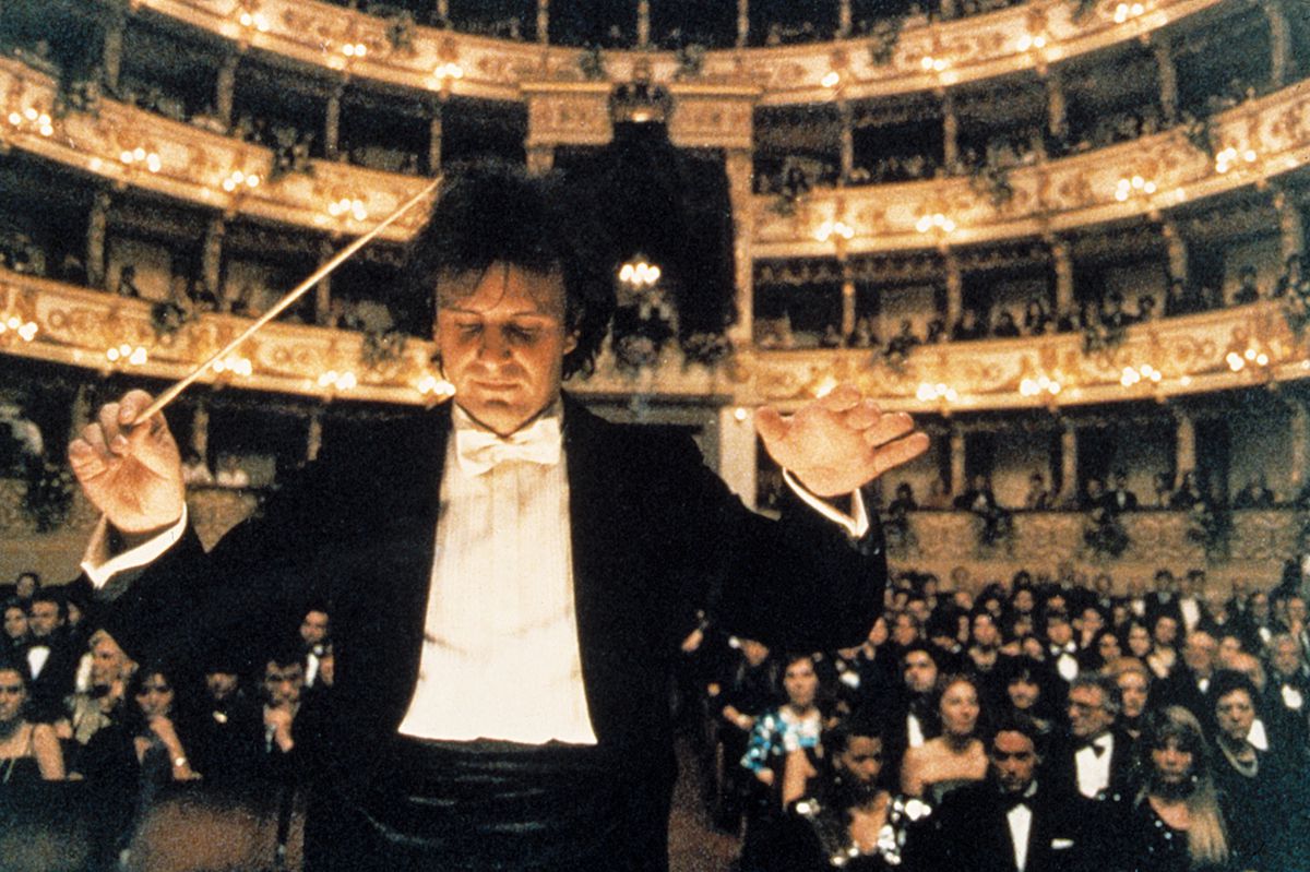 En dirigent står framför en stor teater och leder en orkester i Dario Argentos opera