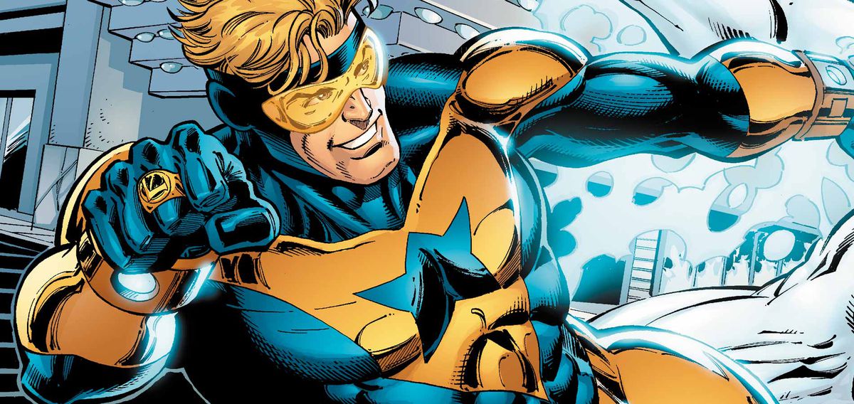 Booster Gold zips away from an energy blast while grinning.