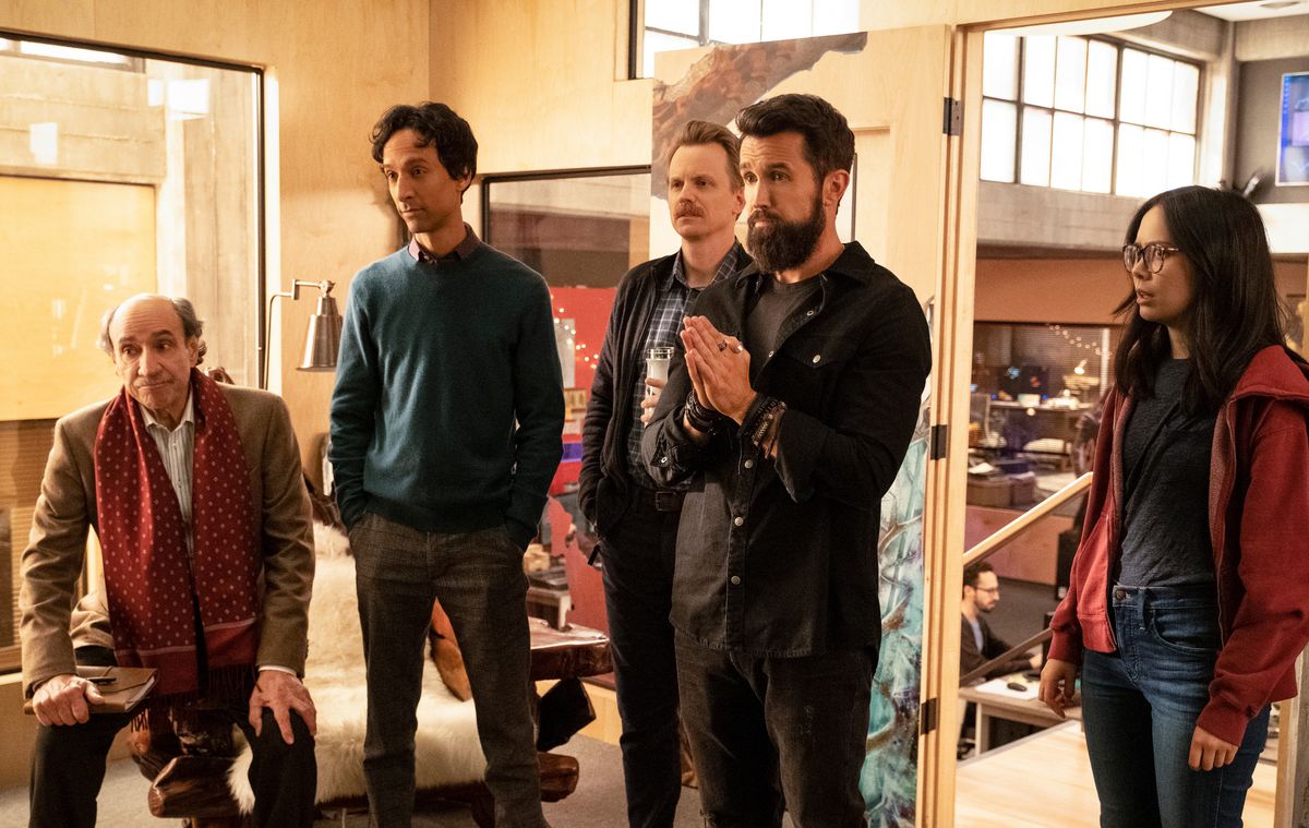 F. Murray Abraham, Danny Pudi, David Hornsby, Rob McElhenney, and Charlotte Nicdao stand in a line with surprised expressions in a video game studio in Mythic Quest: Raven’s Banquet
