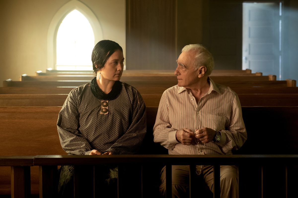 Lily Gladstone och regissören Martin Scorsese sitter tillsammans på en bänk i en kyrka i en bakom kulisserna inspelning från Scorseses Killers of the Flower Moon