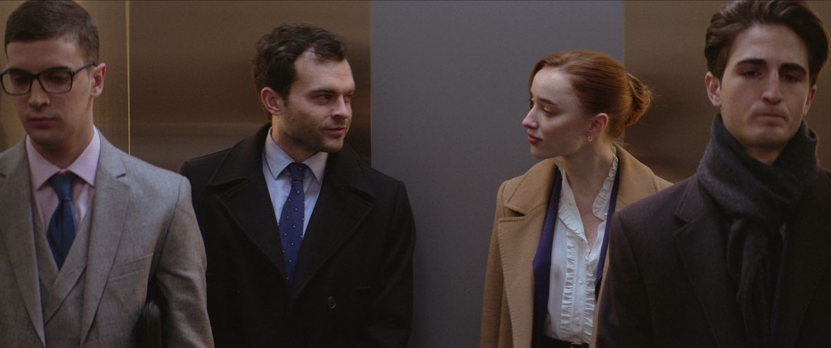 Hemliga älskare Luke (Alden Ehrenreich) och Emily (Phoebe Dynevor), som låtsas inte känna varandra på arbetsplatsen, delar en meningsfull blick i hissen när omedvetna snubbar står runt dem i Netflix Fair Play
