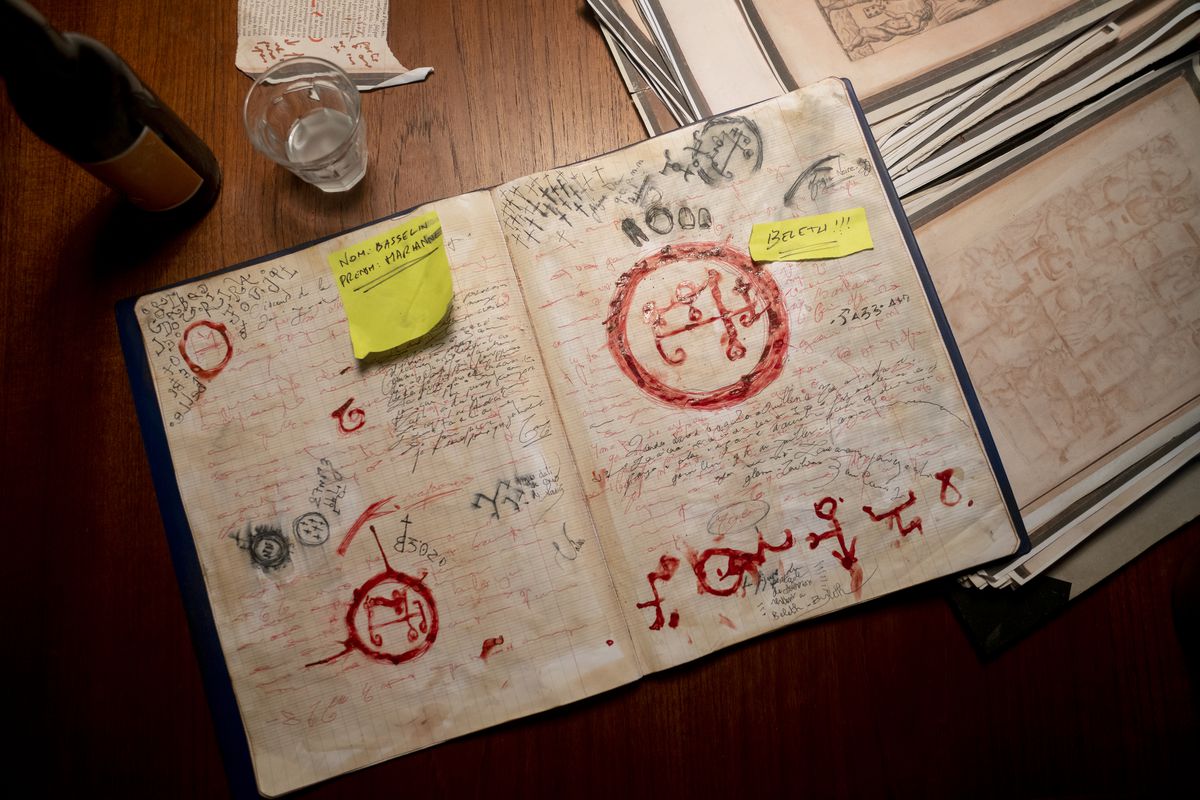 En närbild på en anteckningsbok med några anteckningar nedklottrade och symboler ritade i blod 