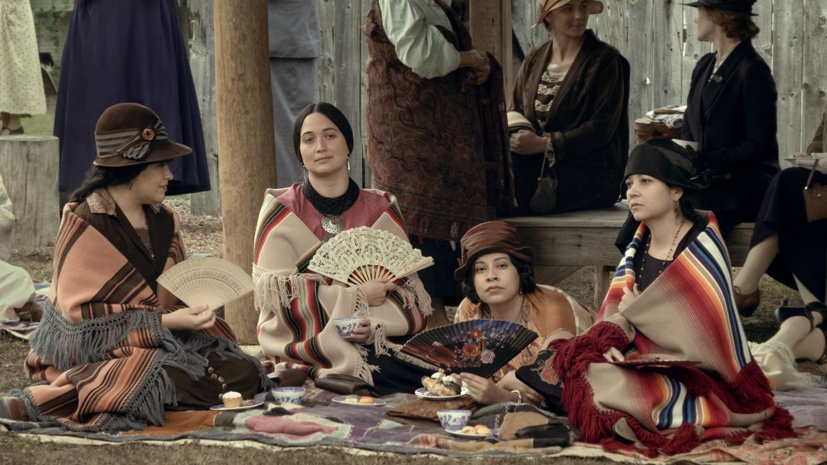 Lily Gladstone, med en fläkt, sitter i mitten av en grupp välklädda Osage-kvinnor i Killers of the Flower Moon