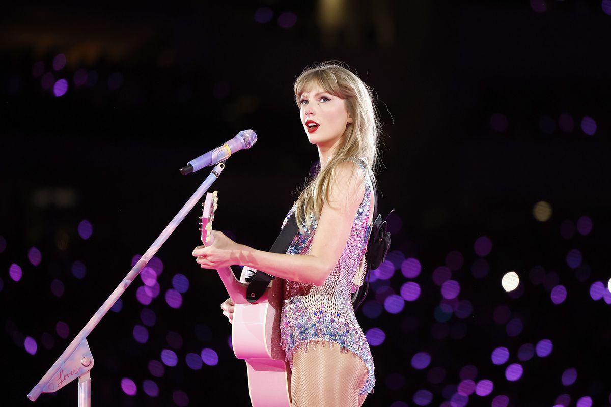 Taylor Swift håller en rosa gitarr och tittar upp till publiken bort från sin mikrofon under Taylor Swift The Eras Tour på SoFi Stadium den 3 augusti 2023 i Inglewood, Kalifornien