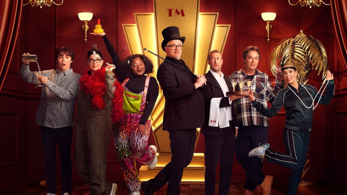 Taskmaster’s Series 16 contestants flank Greg Davies and Alex Horne on stage.