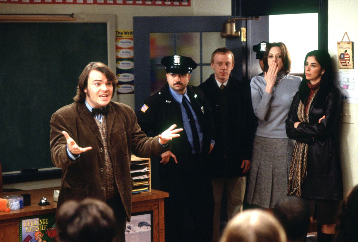 Jack Black, i en kostymjacka i brun tweed, vädjar till sitt klassrum som polis och flera administratörer kommer in i rummet i Richard Linklaters film School of Rock från 2003.