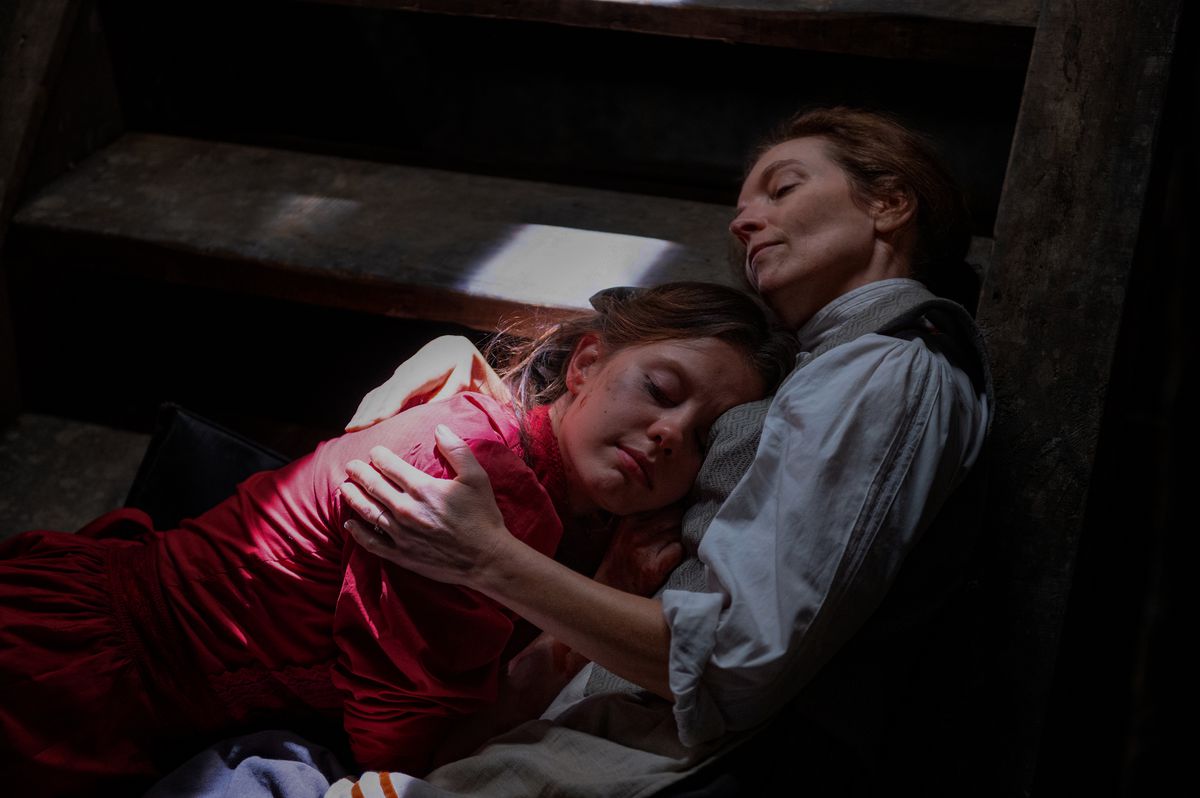 Pearl (Mia Goth) lies on a basement staircase in the arms of her mother Ruth (Tandi Wright) in Ti West’s Pearl