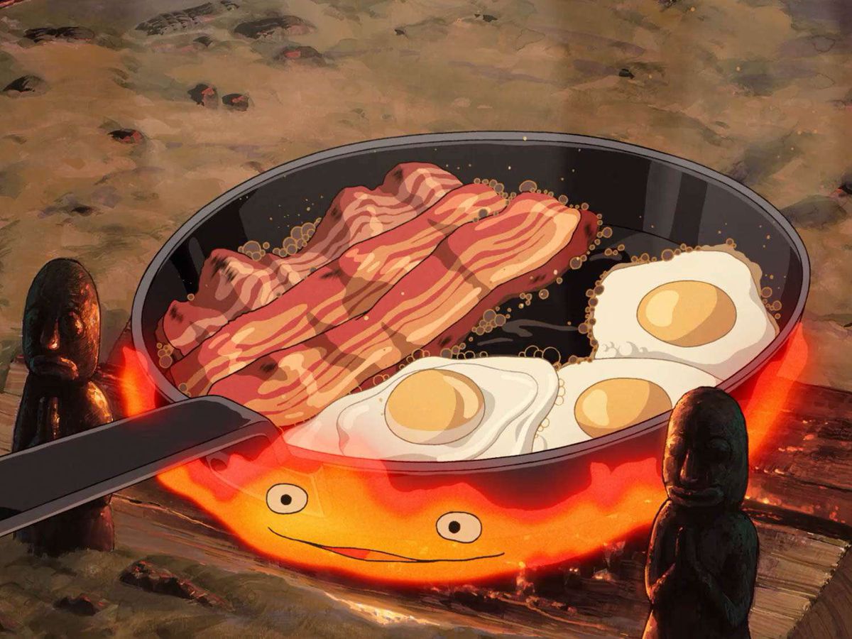 En animerad stekpanna med ägg och tjockskuret bacon som puttrar på en eld med en mun och två ögon i Howl's Moving Castle.