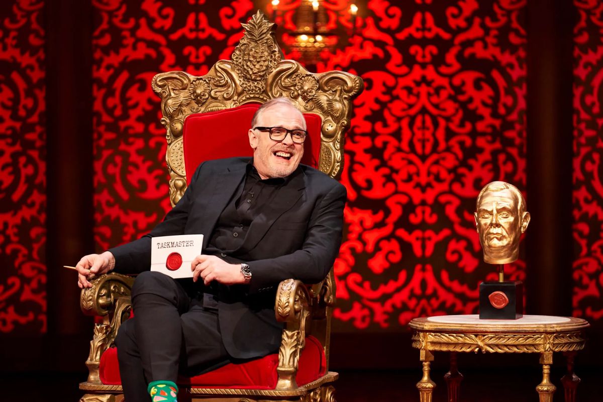 Greg Davies laughs next to a statue of his head in Taskmaster.