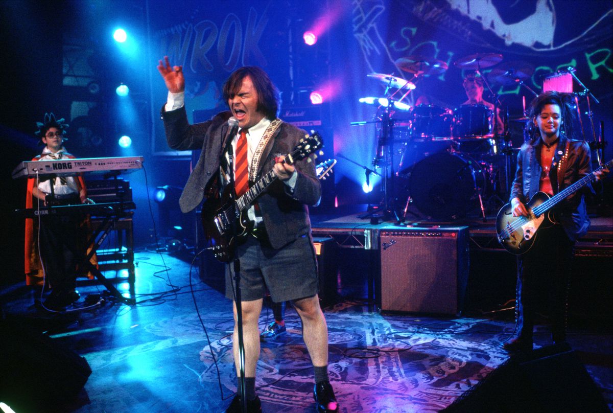Jack Black i kostymjacka, knallröd slips och shorts, gungande vid mikrofonen på scenen i Richard Linklaters film från 2003 School of Rock