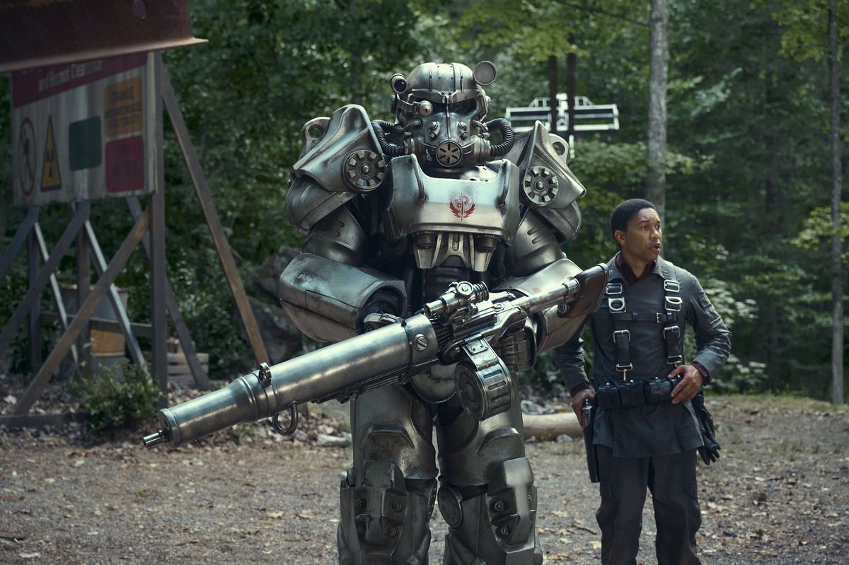 En person i maktrustning står bredvid en vanlig person på en bild från Amazon Prime Videos Fallout-serie