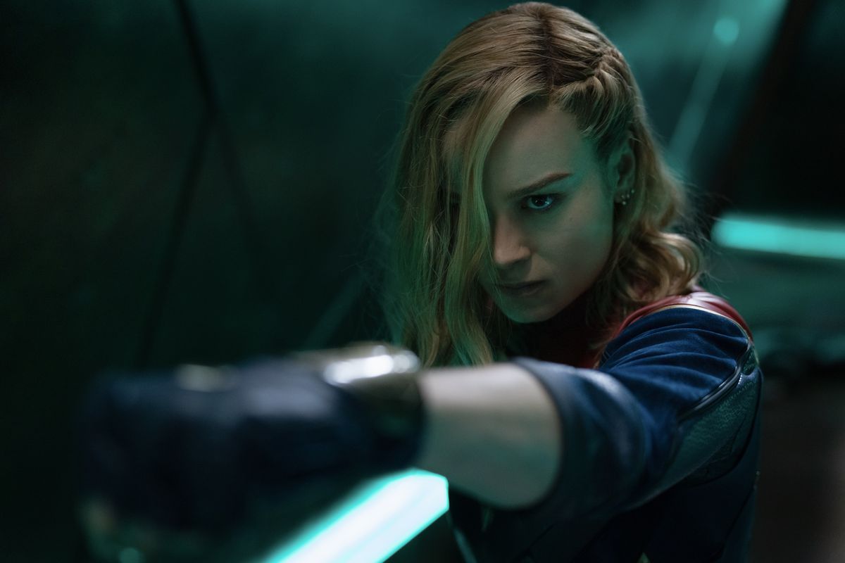 Brie Larson som Captain Marvel i The Marvels håller ut sin hand med hår som täcker en del av hennes ansikte mitt i ett slagsmål