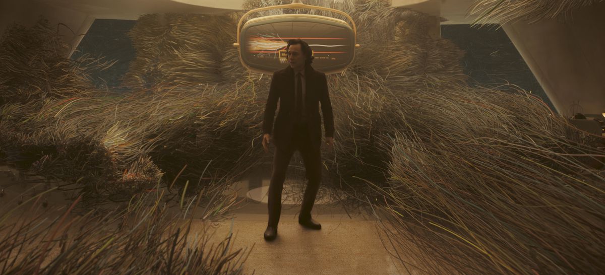 Loki (Tom Hiddleston) står mitt i världen och vänder sig till spagettisträngar