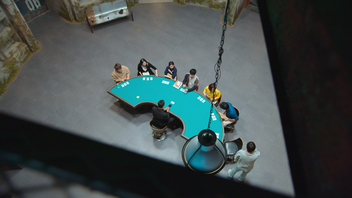 De tävlande i The Devil's Plan sitter runt ett pokerbord i en match.