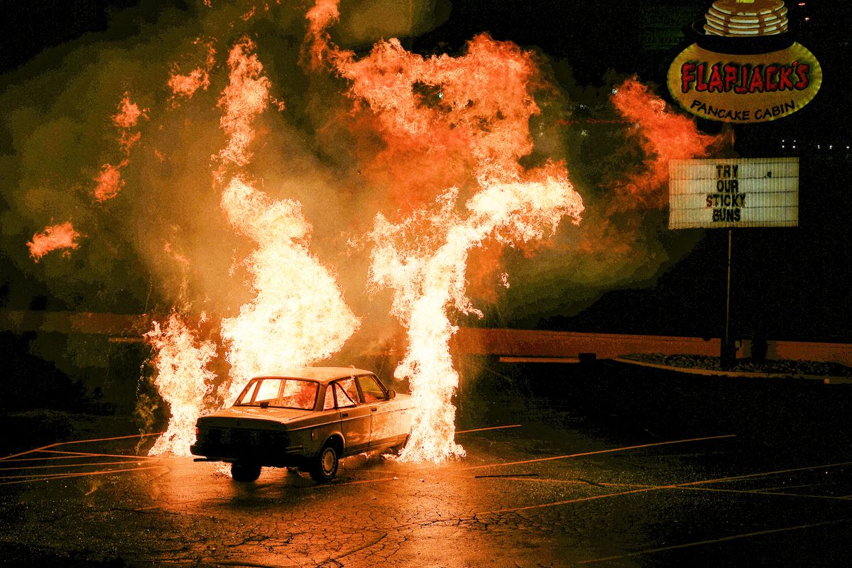 A car on fire in a parking lot in a still from How To with John Wilson