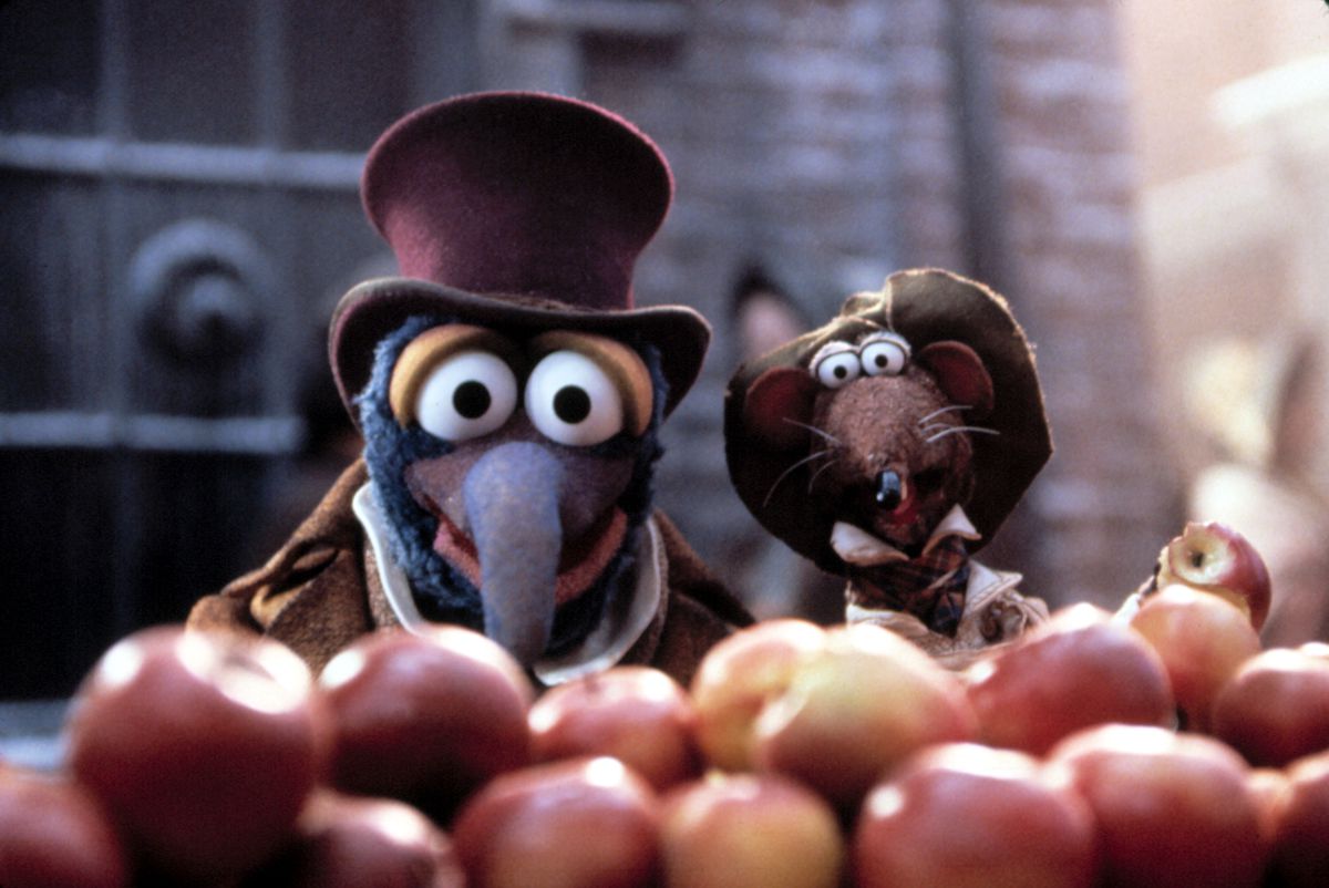 Charles Dickens (Gonzo) and Rizzo stare at the camera humorously over a pile of apples in The Muppet Christmas Carol. 