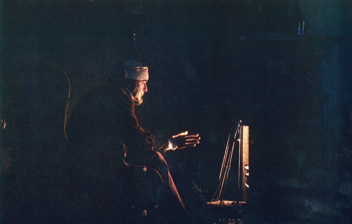 Michael Caine’s Ebeneezer Scrooge crouches by his meagre fire in a dark room in The Muppet Christmas Carol. 