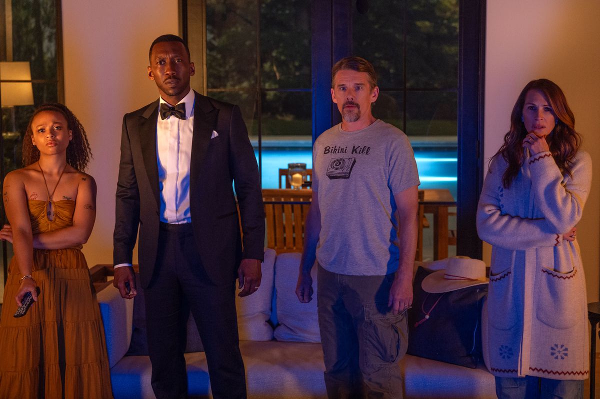 Myha'la, Mahershala Ali, Ethan Hawke och Julia Roberts står bredvid varandra och stirrar oroligt på en tv i Netflix-filmen Leave the World Behind