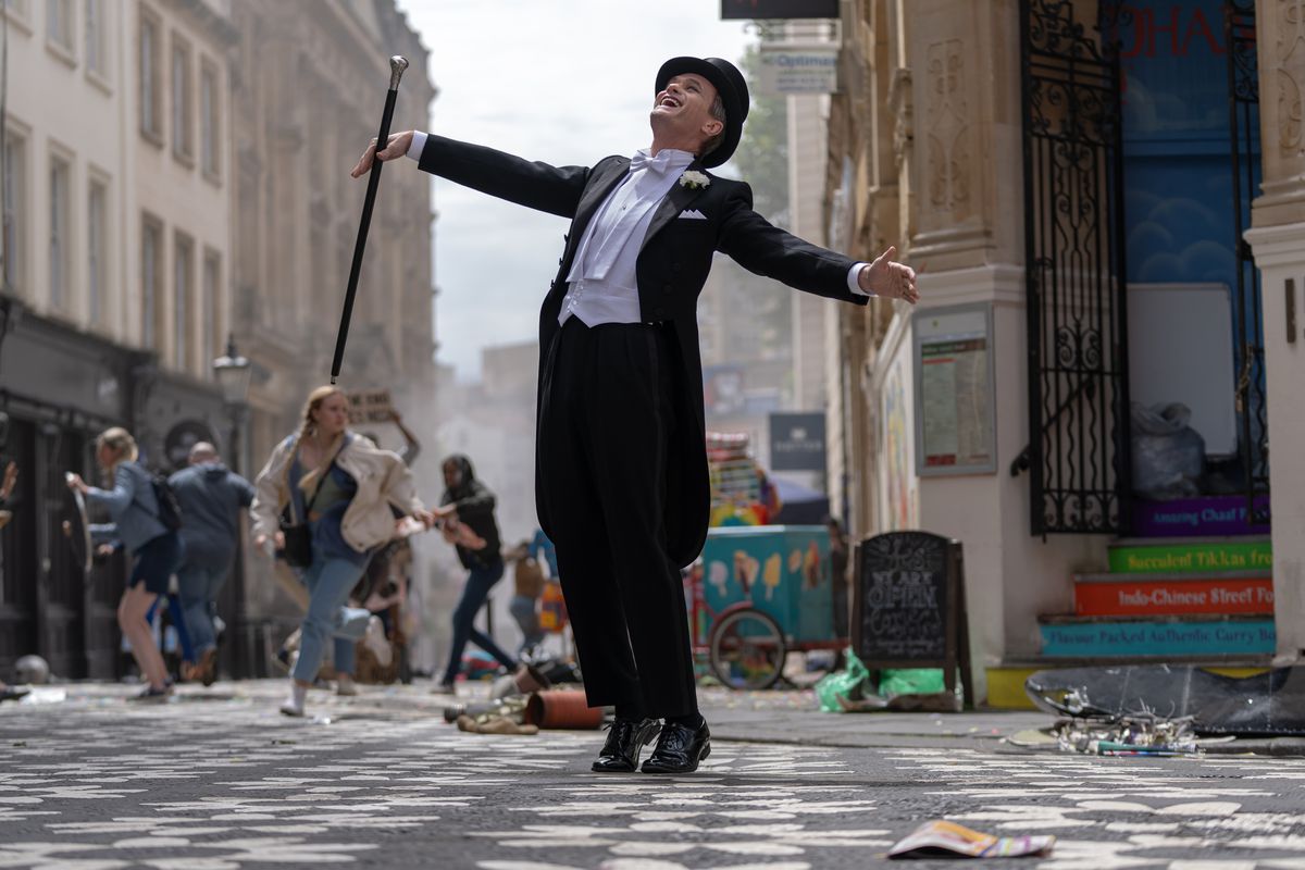 Neil Patrick Harris dansar i smoking med frackar, hög hatt och käpp när kaos bryter ut på Londons gator bakom honom i Doctor Who-specialen 