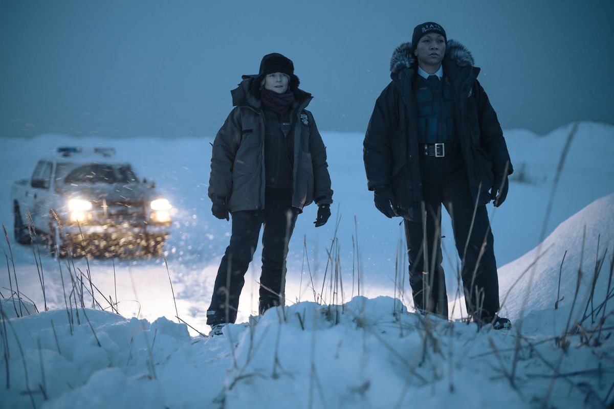 Alaska-detektiverna Liz Danvers och Evangeline Navarro står på en snöig kulle framför sin trupplastbil i HBO-serien True Detective: Night Country.