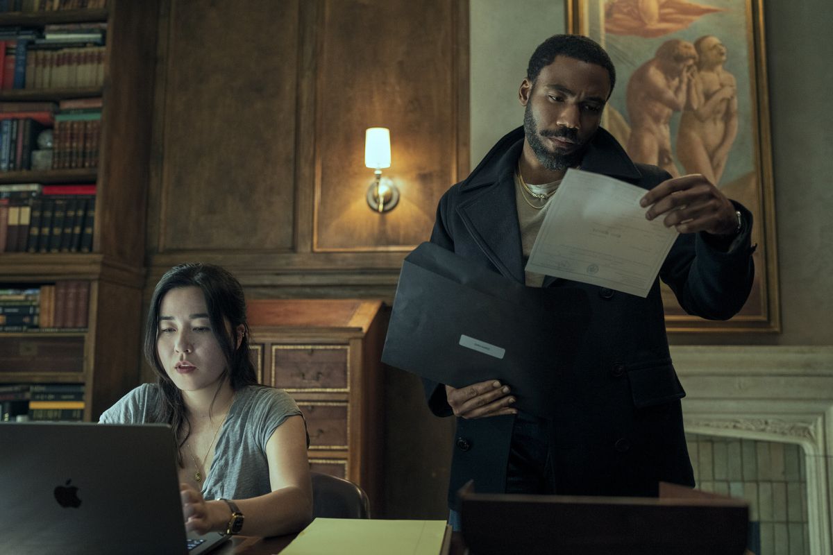 Donald Glover looks at documents while Maya Erskine works on a computer next to him in Mr. & Mrs. Smith the television show