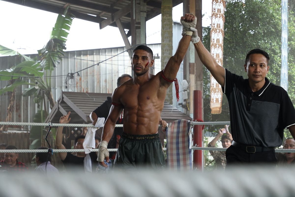 Nassim Lyes, looking absolutely shredded, gets his arm raised in the ring after a fight in Mayhem!