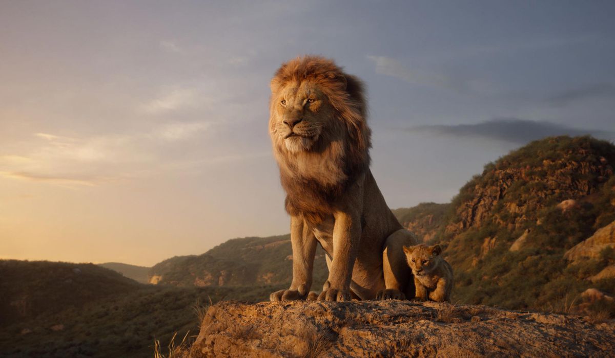 CG Mufasa and Simba stand atop a photorealistic version of Pride Rock in the 2019 remake of The Lion King.