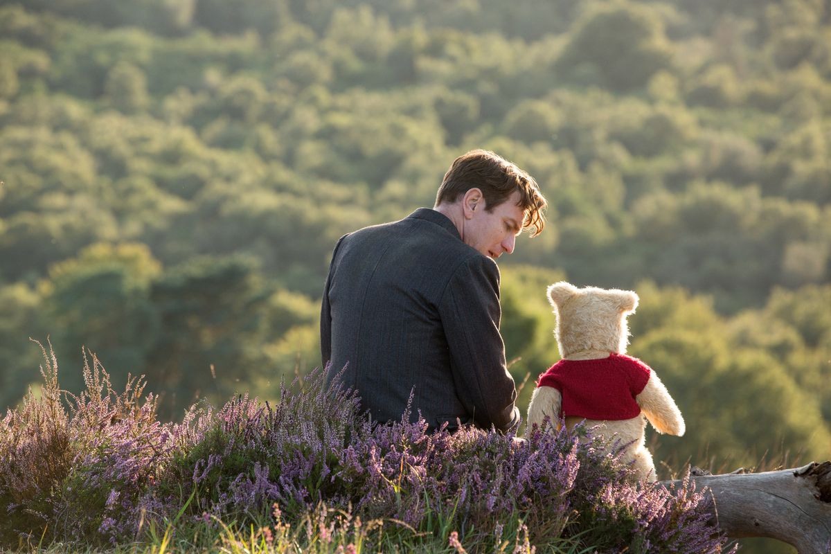 Christopher Robin (Ewan McGregor) sits with his longtime friend Winnie the Pooh in Disney’s live-action adventure Christopher Robin