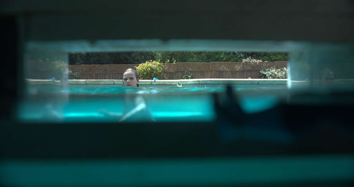 Ett barn tittar mot en poolskimmer, som vi ser från skummarens perspektiv i Night Swim